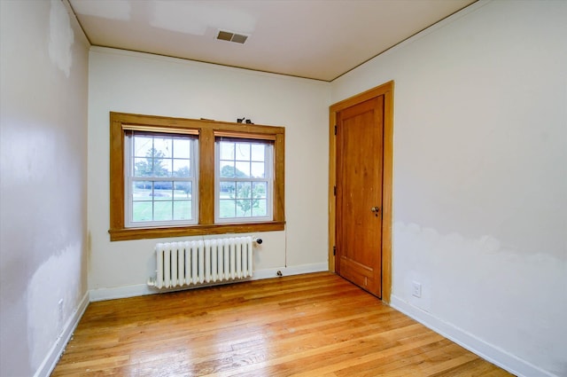 unfurnished room featuring radiator heating unit, light hardwood / wood-style floors, and ornamental molding