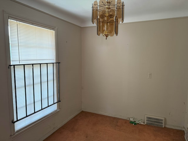 spare room featuring carpet floors and an inviting chandelier