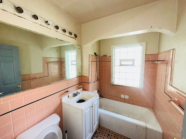 full bathroom with tiled shower / bath, vanity, toilet, and tile walls