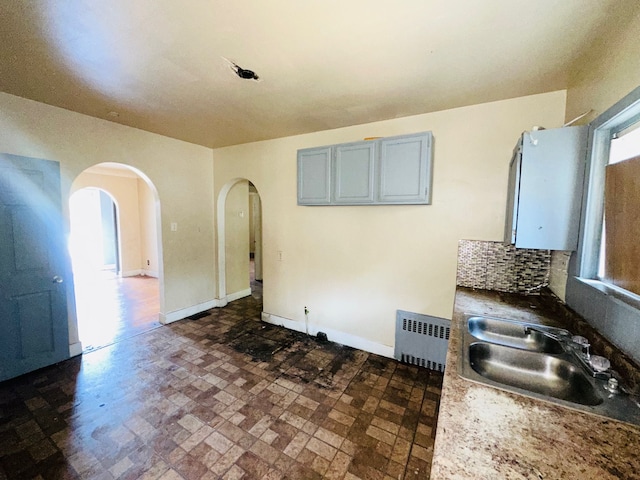 kitchen with gray cabinets, radiator heating unit, sink, and tasteful backsplash