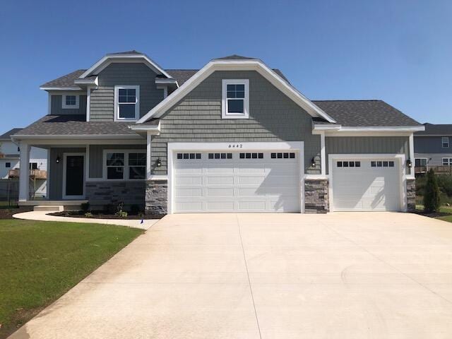 craftsman inspired home featuring a porch, a garage, and a front lawn