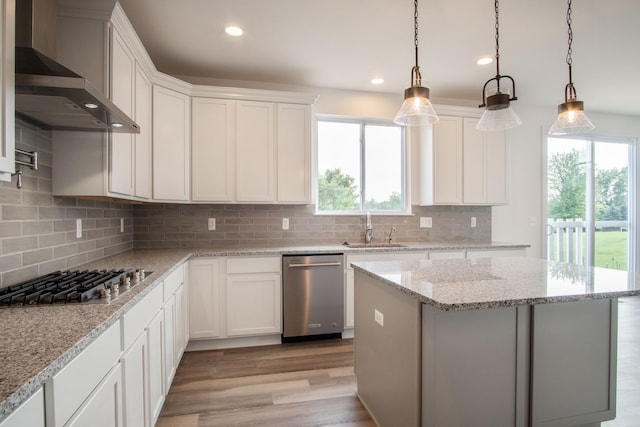 kitchen with appliances with stainless steel finishes, wall chimney exhaust hood, sink, light hardwood / wood-style flooring, and white cabinetry