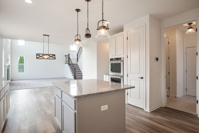 kitchen featuring a kitchen island, white cabinetry, hanging light fixtures, and light hardwood / wood-style flooring