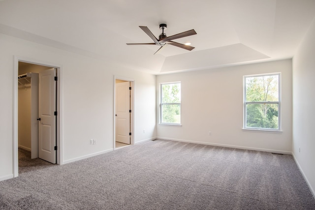 carpeted spare room with ceiling fan and a tray ceiling