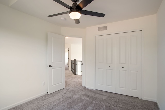 unfurnished bedroom with light carpet, a closet, and ceiling fan