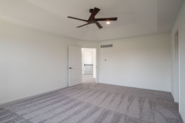 carpeted empty room featuring a raised ceiling and ceiling fan