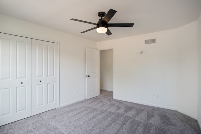 unfurnished bedroom featuring ceiling fan, light colored carpet, and a closet