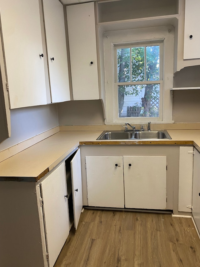 kitchen with white cabinetry, sink, and light hardwood / wood-style flooring