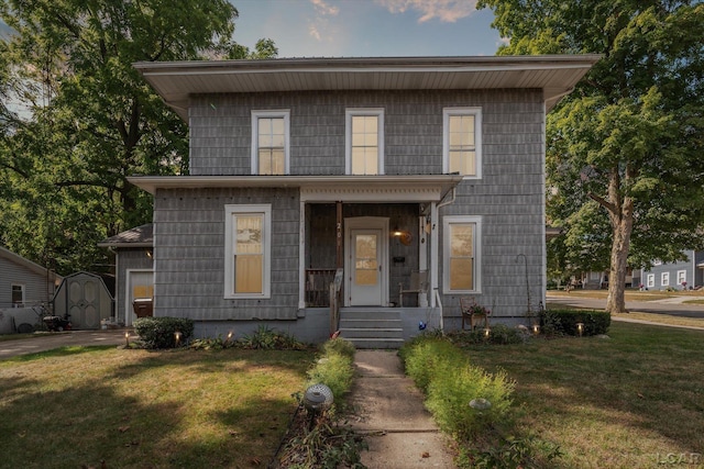 view of front of house featuring a front lawn and a storage shed