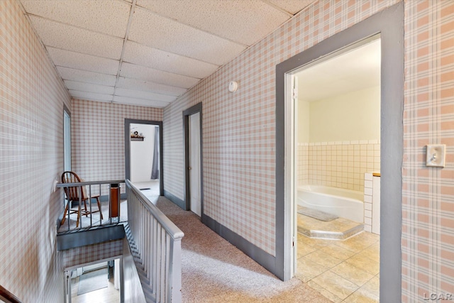 hallway featuring light carpet and a drop ceiling