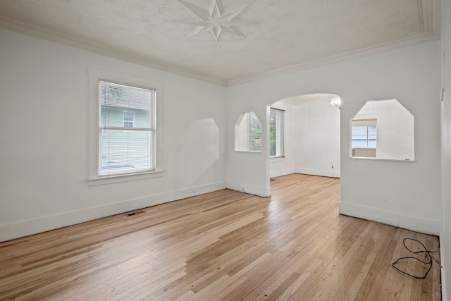 spare room with a textured ceiling, light hardwood / wood-style floors, and ornamental molding