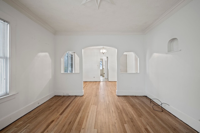 unfurnished room featuring a chandelier, crown molding, and light hardwood / wood-style floors