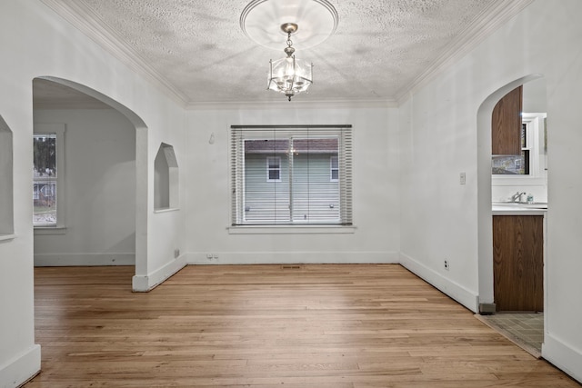 unfurnished dining area featuring a textured ceiling, light hardwood / wood-style floors, and crown molding