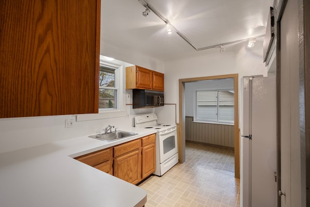 kitchen with rail lighting, white appliances, and sink