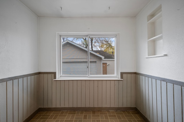 unfurnished room with built in features and wooden walls