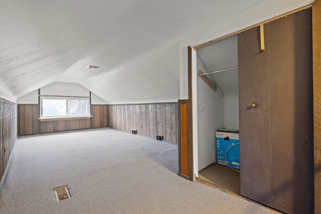 bonus room featuring light colored carpet, vaulted ceiling, and wooden walls