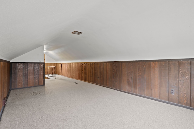 bonus room featuring wood walls, light colored carpet, and lofted ceiling