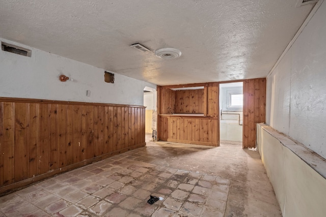 empty room featuring a textured ceiling and wooden walls