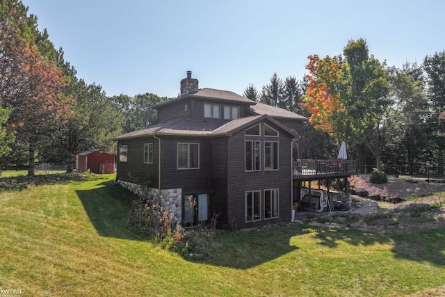 rear view of property featuring a lawn, a storage unit, and a wooden deck