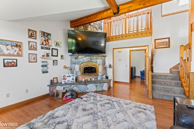 living room with a stone fireplace, lofted ceiling with beams, and light hardwood / wood-style floors