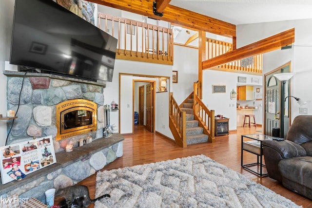 living room featuring a stone fireplace, light hardwood / wood-style flooring, and lofted ceiling with beams