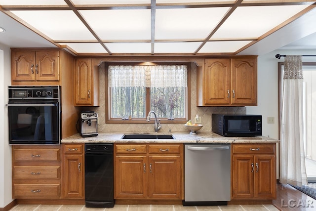 kitchen with tasteful backsplash, light stone counters, sink, and black appliances