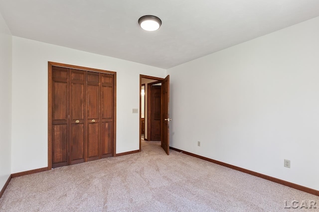 unfurnished bedroom with light carpet and a closet