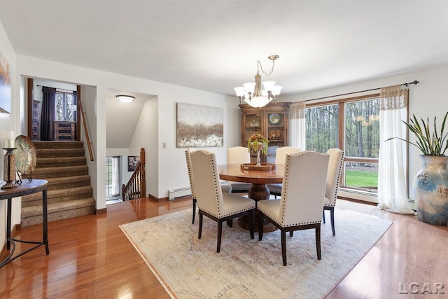 dining room featuring plenty of natural light, an inviting chandelier, a baseboard radiator, and wood-type flooring