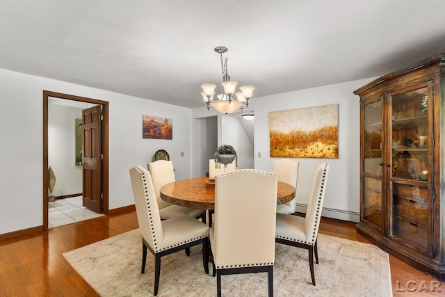 dining area with an inviting chandelier, light hardwood / wood-style flooring, and a baseboard heating unit