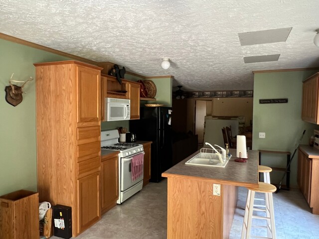 9996 N Chippewa Rd, Coleman, MI 48618 - kitchen with white appliances, a sink, a breakfast bar, light floors, and an island with sink