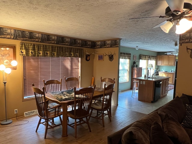 dining space with ceiling fan, sink, light hardwood / wood-style floors, and a textured ceiling