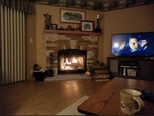 sitting room with hardwood / wood-style flooring and a stone fireplace