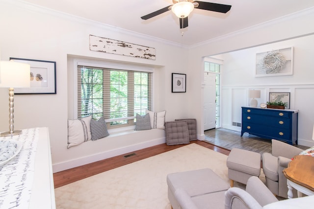 living room featuring ceiling fan, wood-type flooring, and crown molding