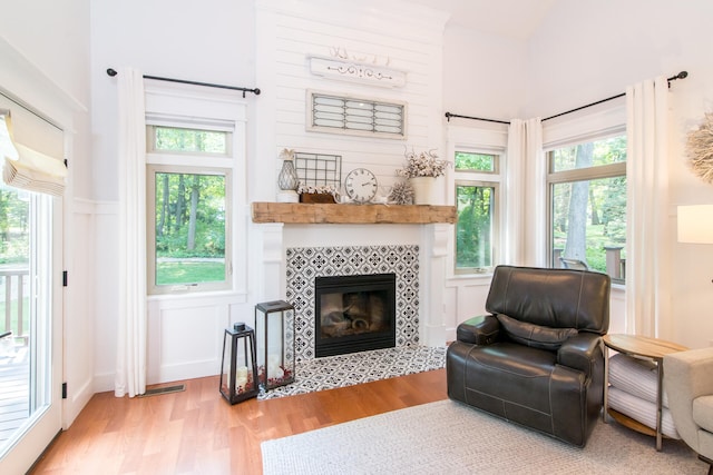 living area featuring plenty of natural light, a tiled fireplace, and light hardwood / wood-style flooring