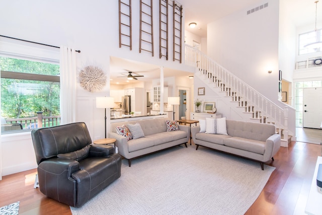 living room featuring ceiling fan, a high ceiling, and hardwood / wood-style flooring