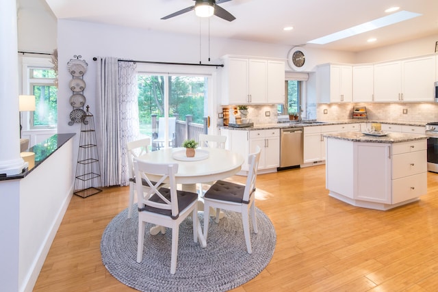 kitchen with a wealth of natural light, stainless steel appliances, light hardwood / wood-style flooring, and a skylight