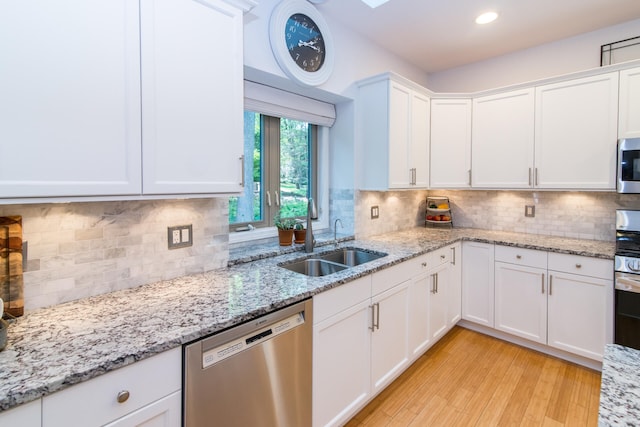 kitchen with backsplash, white cabinets, sink, light hardwood / wood-style flooring, and stainless steel appliances