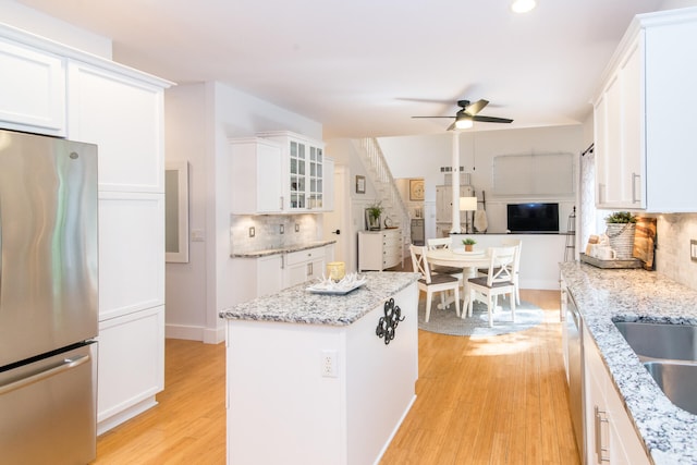 kitchen featuring backsplash, white cabinets, light wood-type flooring, and appliances with stainless steel finishes