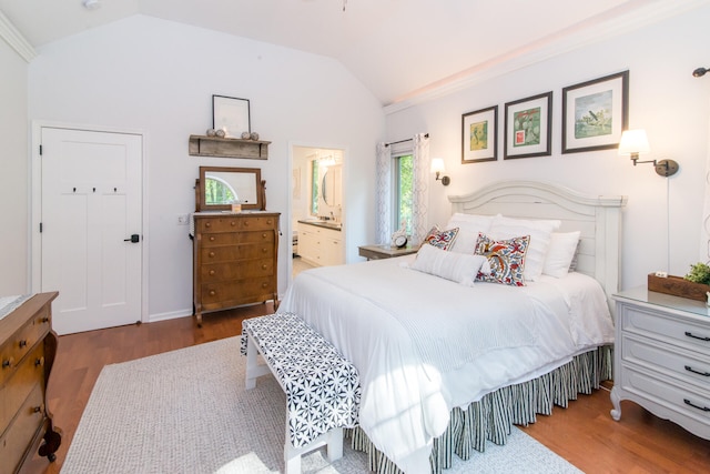 bedroom featuring dark hardwood / wood-style flooring, ensuite bathroom, and vaulted ceiling