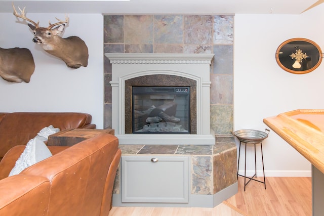 living room with light wood-type flooring and a tiled fireplace