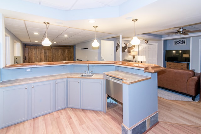 kitchen with dishwasher, sink, hanging light fixtures, ceiling fan, and light wood-type flooring