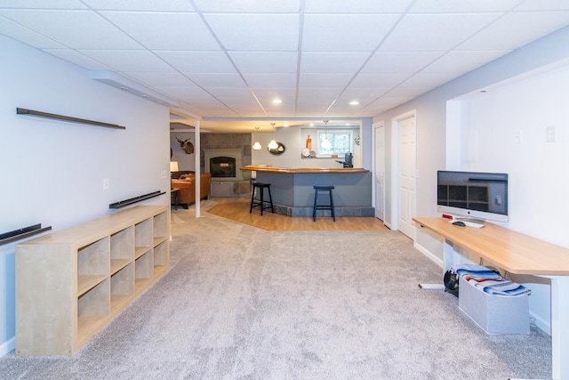 interior space with a fireplace, a drop ceiling, and light wood-type flooring