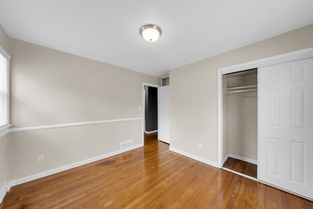 unfurnished bedroom featuring a closet and hardwood / wood-style flooring