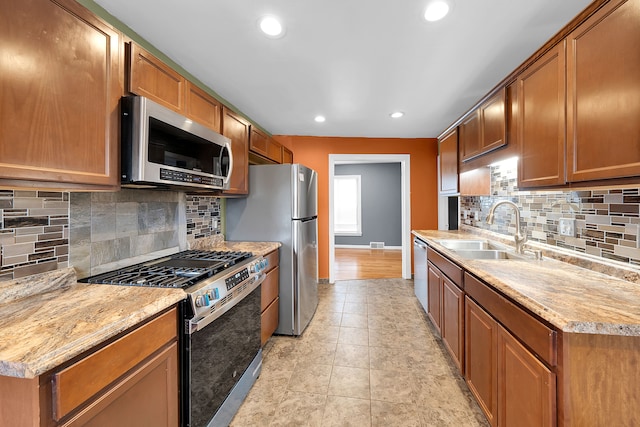 kitchen with tasteful backsplash, light stone counters, sink, and stainless steel appliances