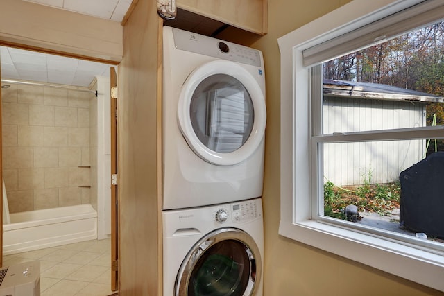 washroom featuring light tile patterned floors, stacked washer / dryer, and a wealth of natural light