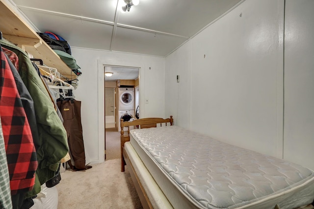 bedroom with carpet floors and stacked washer / dryer