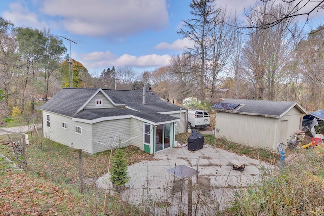 back of property featuring a sunroom, an outbuilding, and a patio