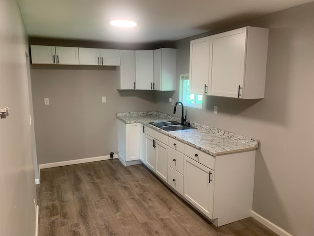 kitchen featuring light stone counters, dark hardwood / wood-style flooring, white cabinetry, and sink