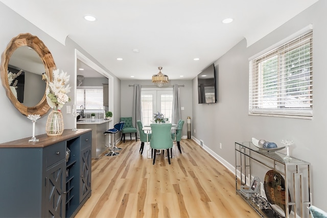 dining room featuring sink, a healthy amount of sunlight, and light hardwood / wood-style floors