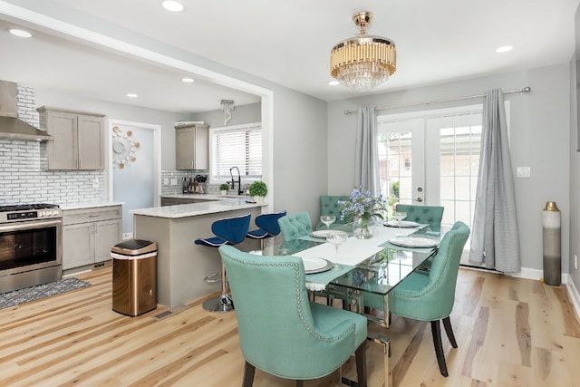 dining room featuring sink, french doors, a notable chandelier, and light wood-type flooring